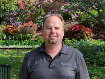 Man in dark grey shirt standing in a park