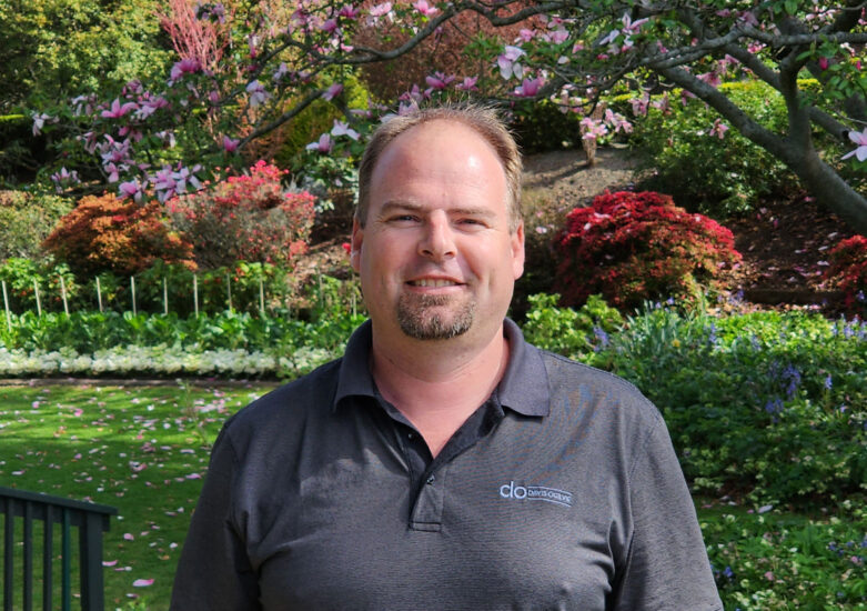 Man in dark grey shirt standing in a park