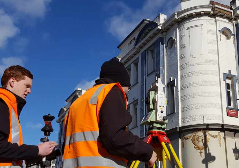 Two men with hi-vis with survey equipment on a sunny day