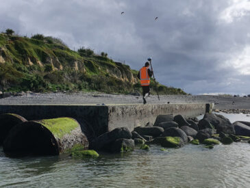 Man dressed in orange walking nearby the side of a river