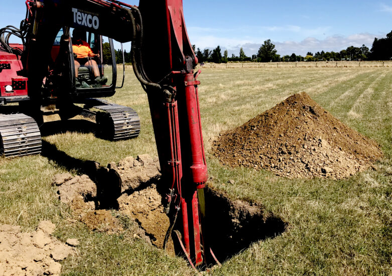 Digger in hole in a field on a sunny day