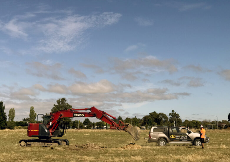 Digger and truck in field on a sunny day