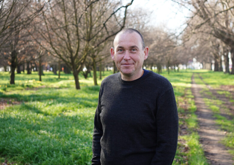 Man in a dark jumper standing in a park